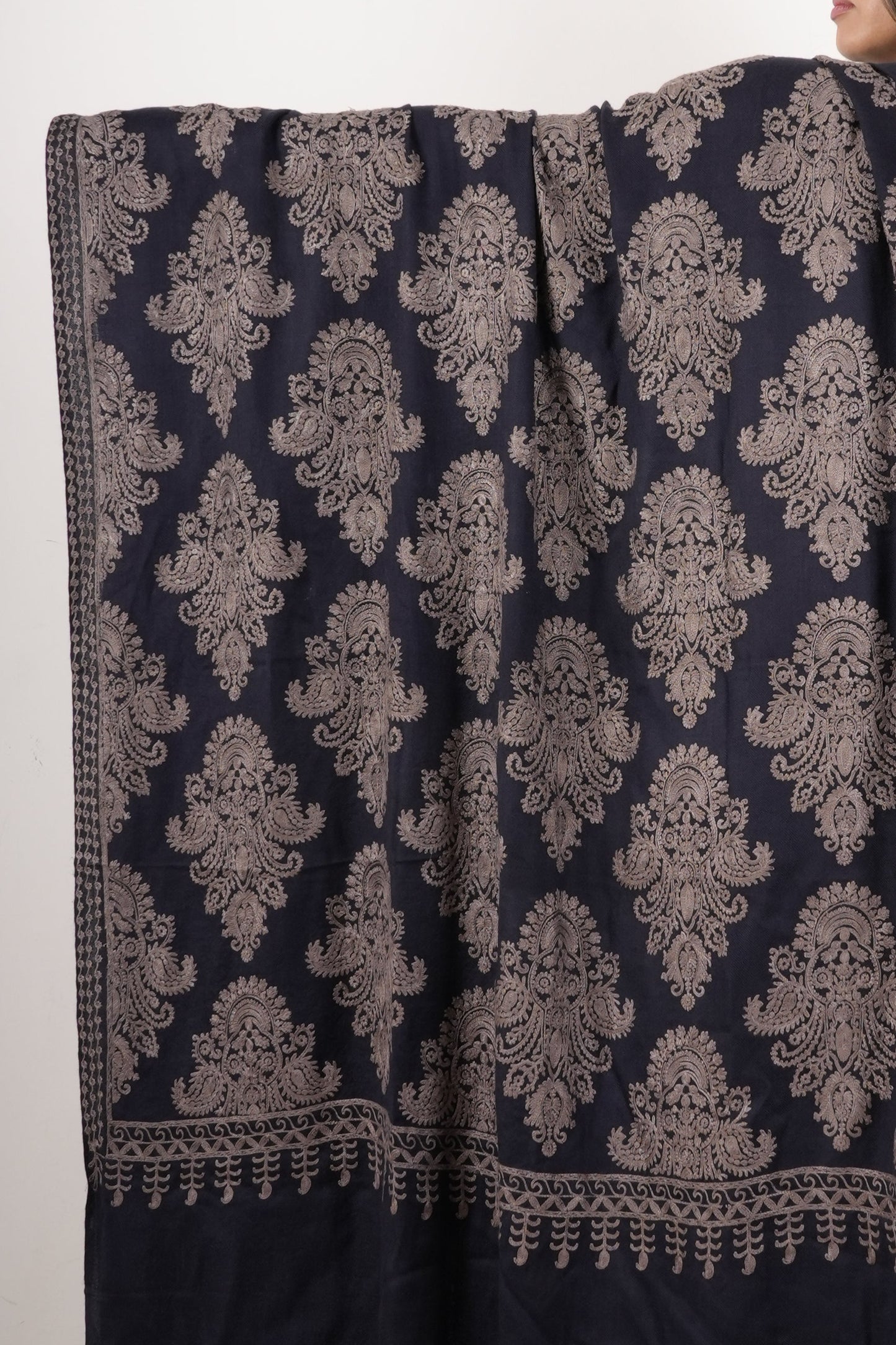 Woman holding a large dark blue and gold patterned fabric on a plain background