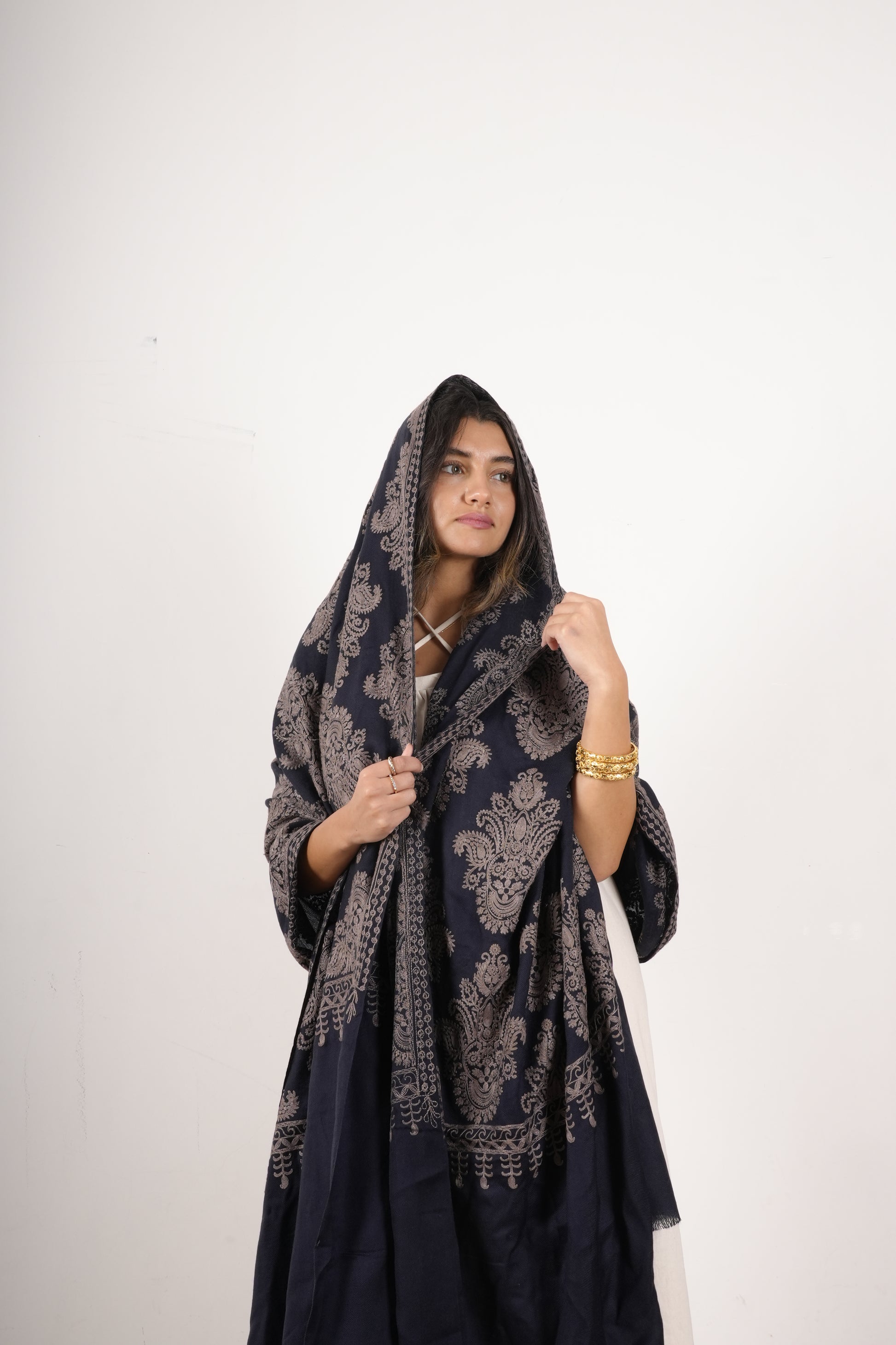 Woman wearing a dark blue embroidered shawl  on a white background